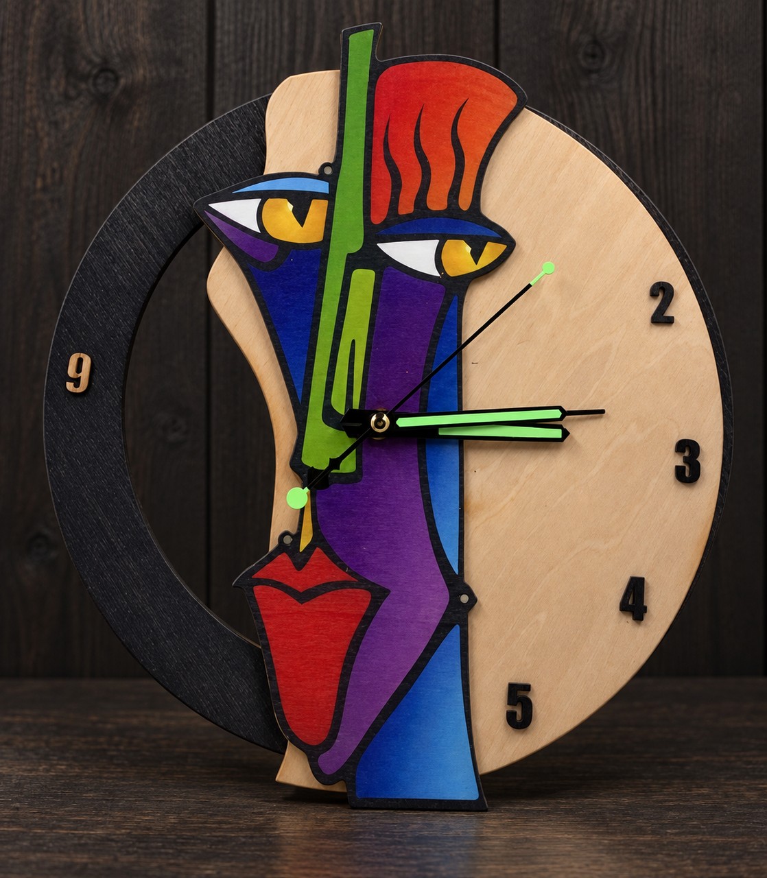Reference HO 4 — colourful abstract face-shaped wooden clock on a dark studio background, 29 cm diameter