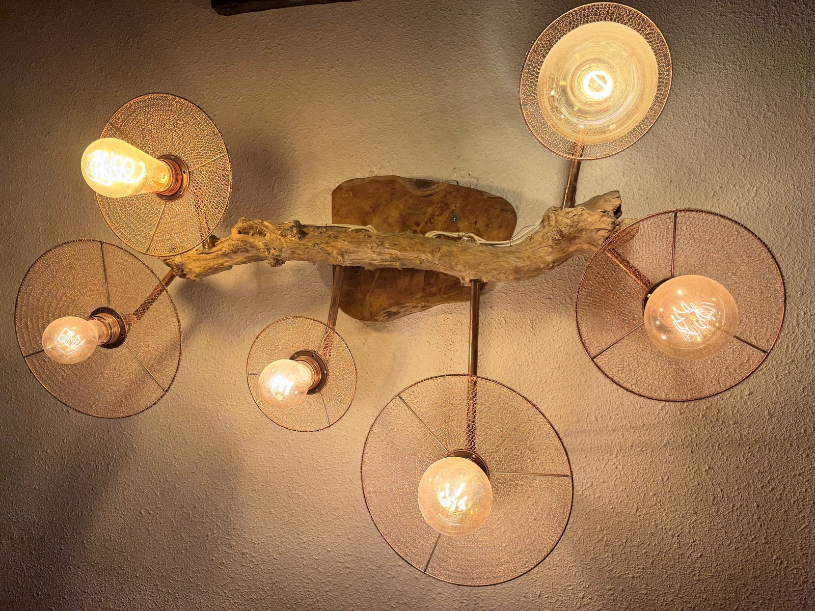 Reference LMR 2a — large illuminated wall lamp with six circular hand-crocheted copper-wire shades, reclaimed copper water pipe and driftwood
